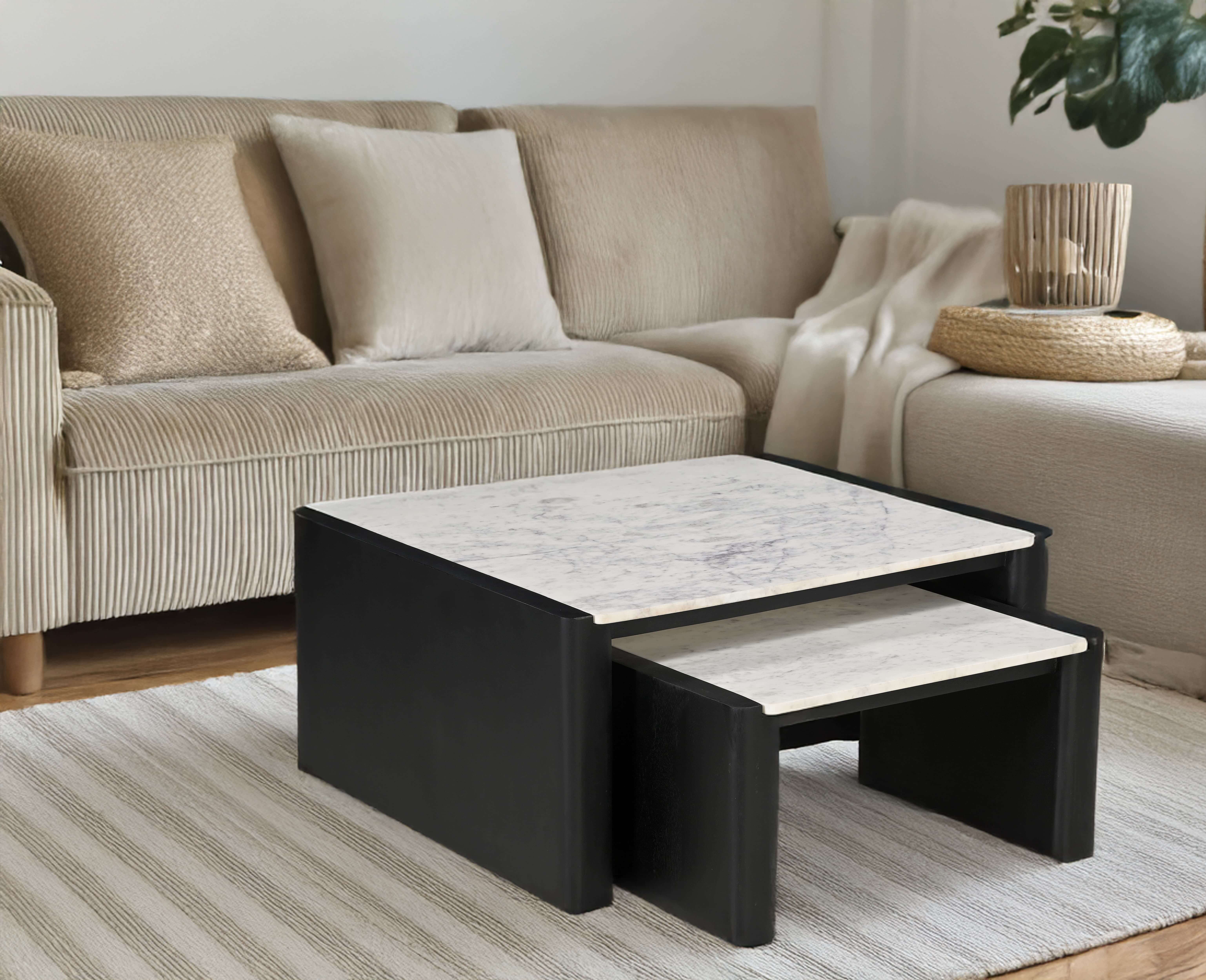 Modern marble-top nesting coffee table set with black frame placed on a striped rug in a beige-toned living room.