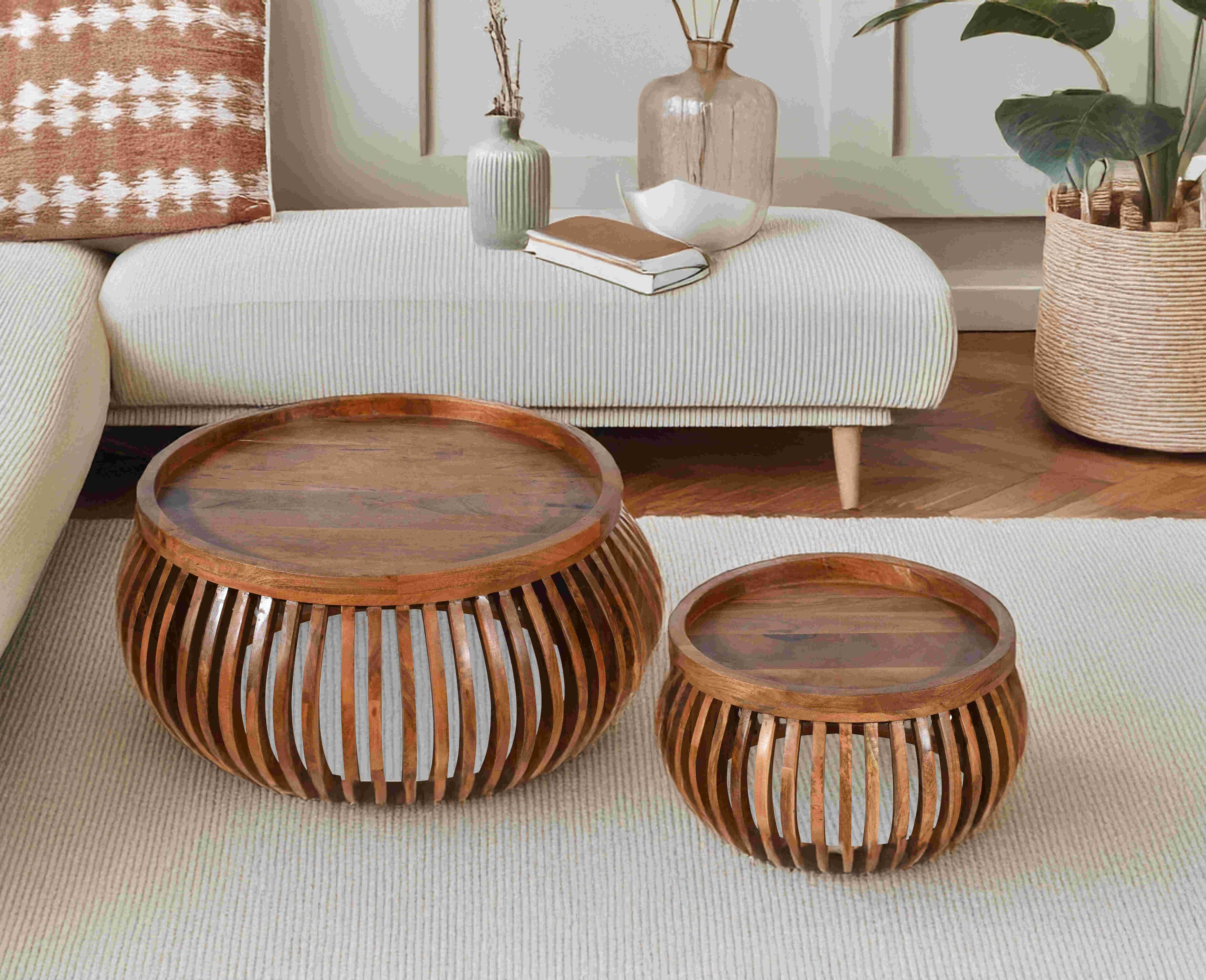 Pair of round wooden coffee tables with slatted barrel design and solid tops, styled on a textured rug near a cream sofa with cozy decor.