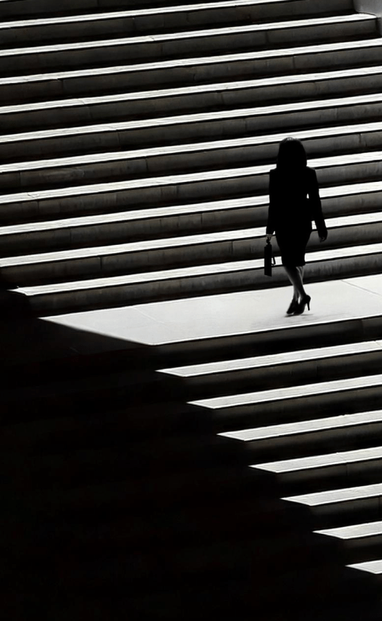 Anwältin steigt mühsame Treppe hinauf – ein Sinnbild für die zeitaufwändige Rechtsrecherche ohne KI.