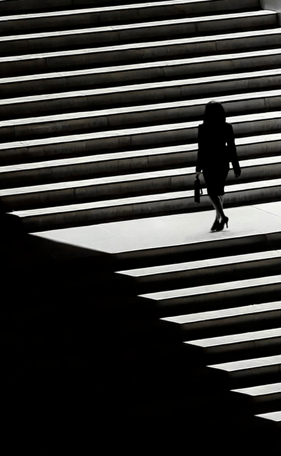 Anwältin steigt mühsame Treppe hinauf – ein Sinnbild für die zeitaufwändige Rechtsrecherche ohne KI.