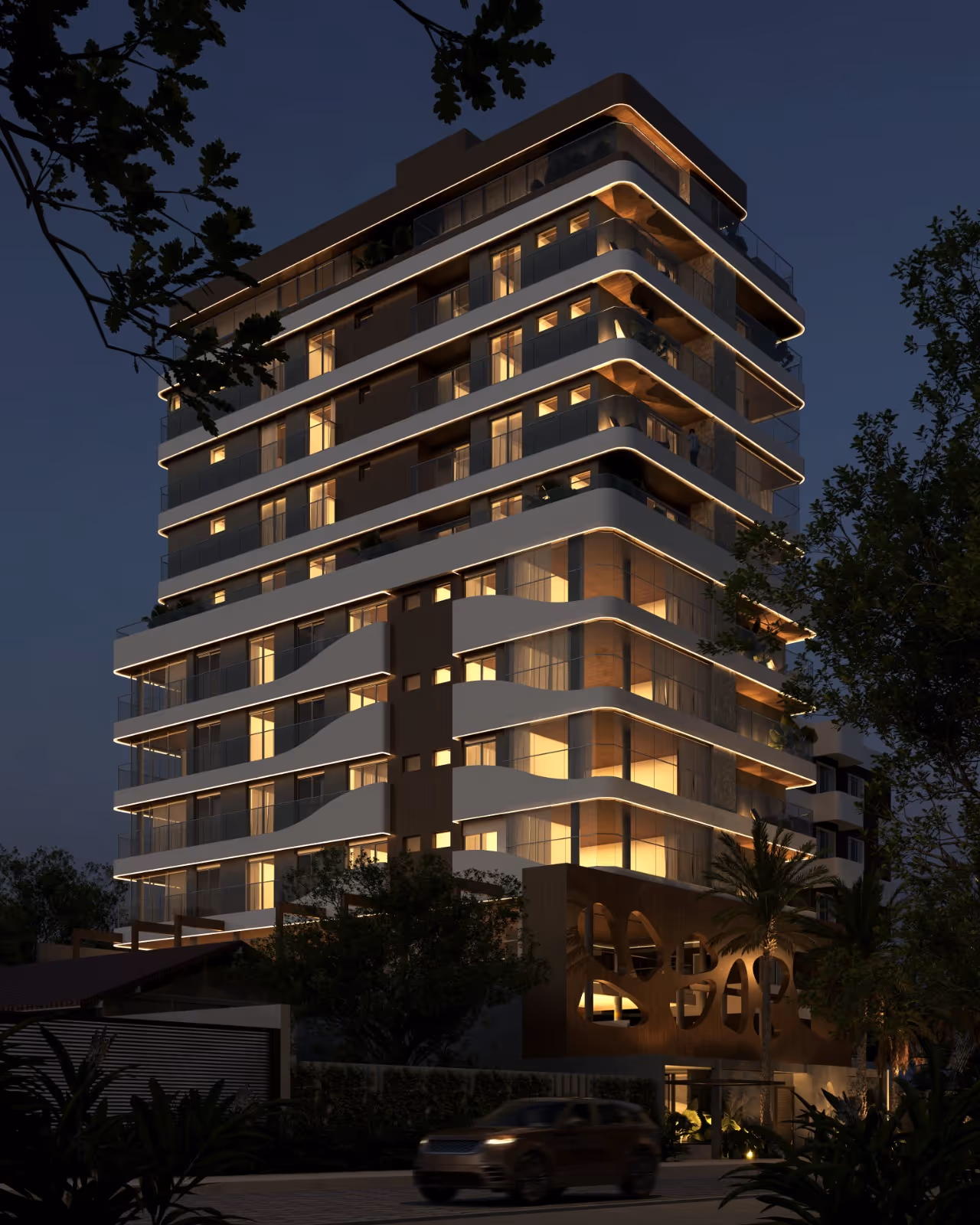 Prédio residencial moderno de vários andares iluminado à noite com varandas e design arquitetônico curvo e iluminação linear.