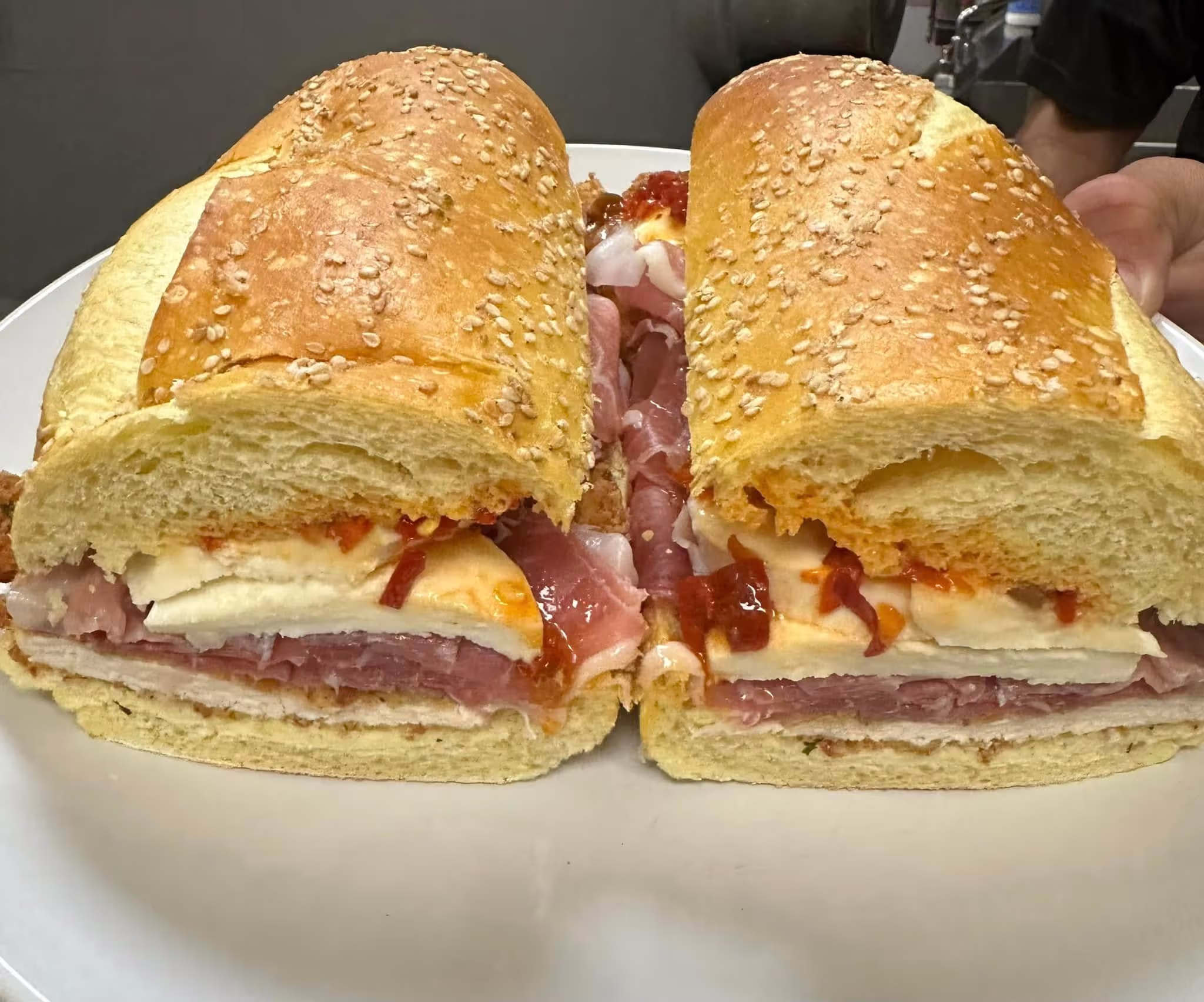 A sandwich with meat and cheese on a white plate.