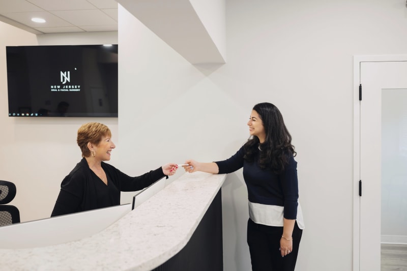 Female staff member at reception desk assisting patient during consultation check-in
