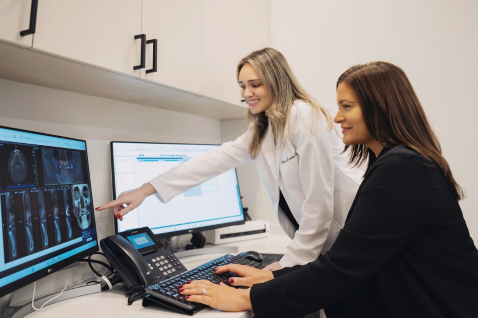 Two clinicians reviewing treatment results on computer monitor showing detailed analysis