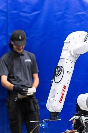 A person standing in front of a white robotAI-generated content may be incorrect.