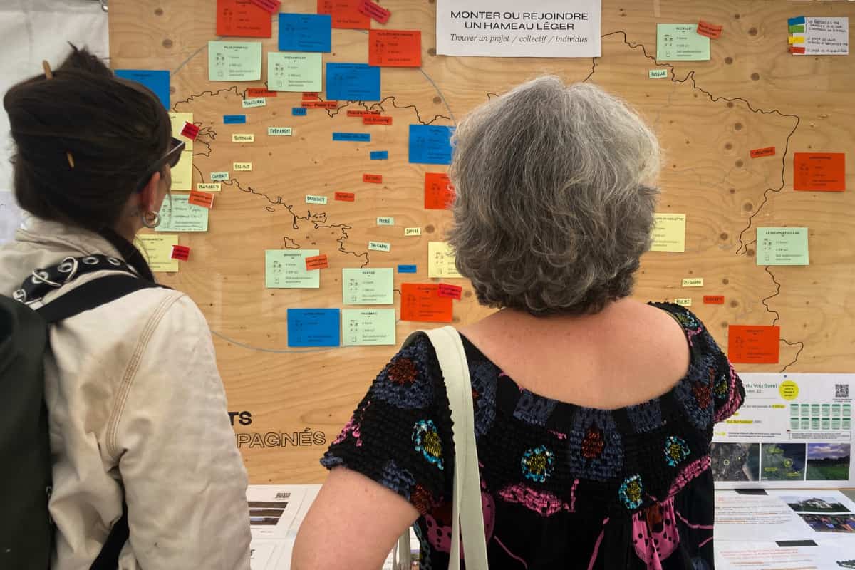 Deux visiteurs devant la carte des projets de hameau léger accompagnés