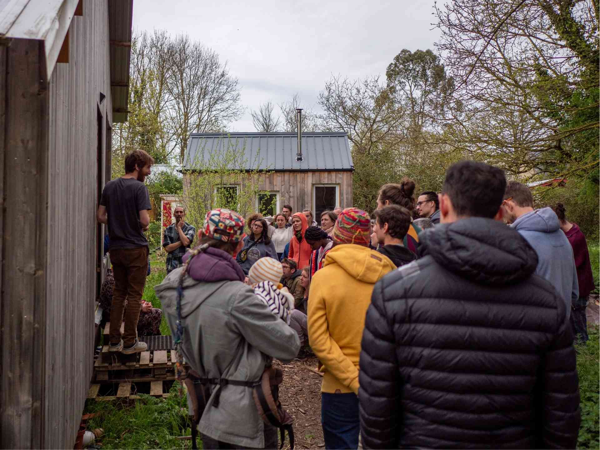 Visiteurs assistant à une présentation lors de de portes ouvertes d'un hameau léger