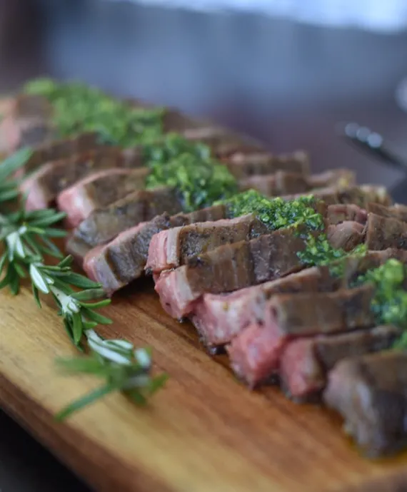 Sliced meat on a butcher board served up for a family style dinner.
