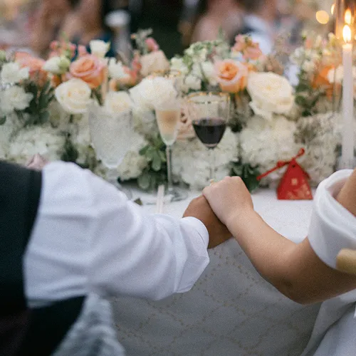 A couple holding hands at the couple's table. 
