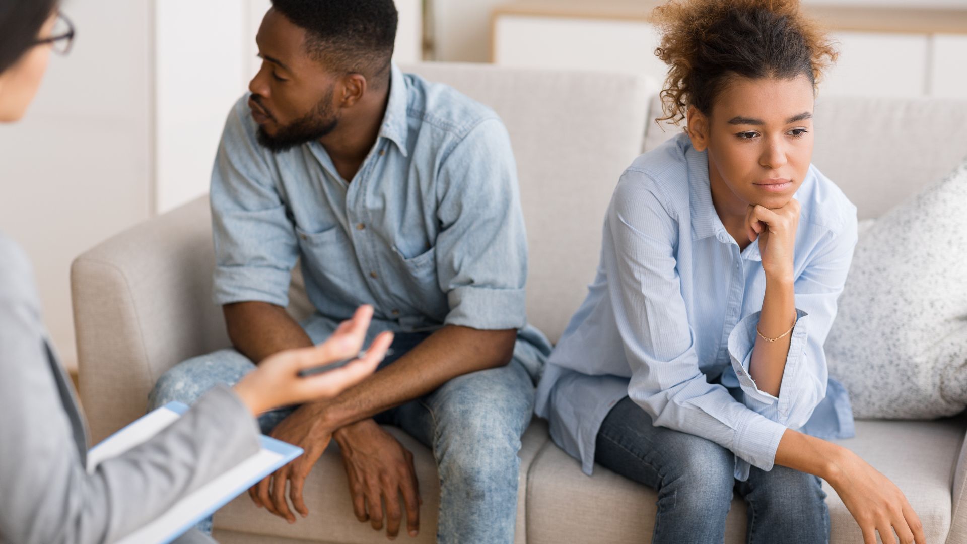 Vater und Tochter sitzen mit Abstand auf einem Sofa bei Beratungsgespräch