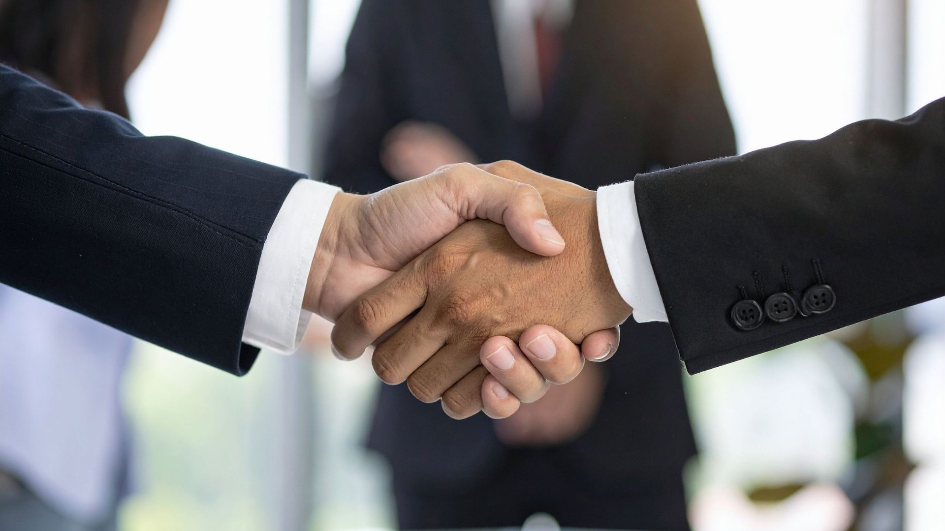 Zwei Personen in Businesskleidung geben sich die Hand