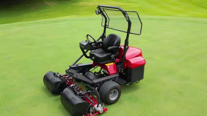 Red riding lawn mower with multiple cutting reels on a green golf course.