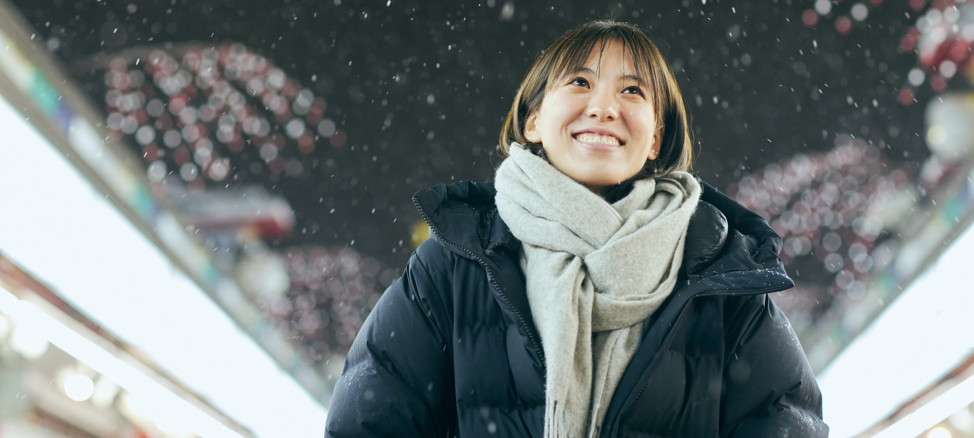 Woman wearing winter coat and scarf smiling.