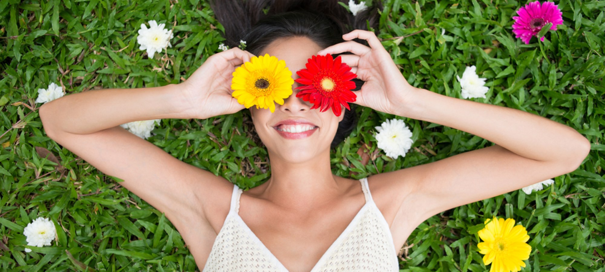 lady lying on grass with flowers over eyes