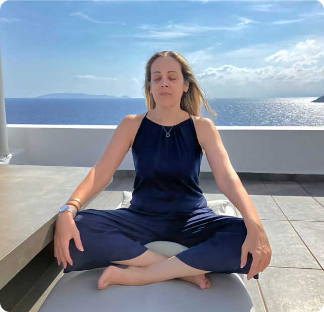 Katerina Lapati practicing meditation at a hotel balcony near the sea.