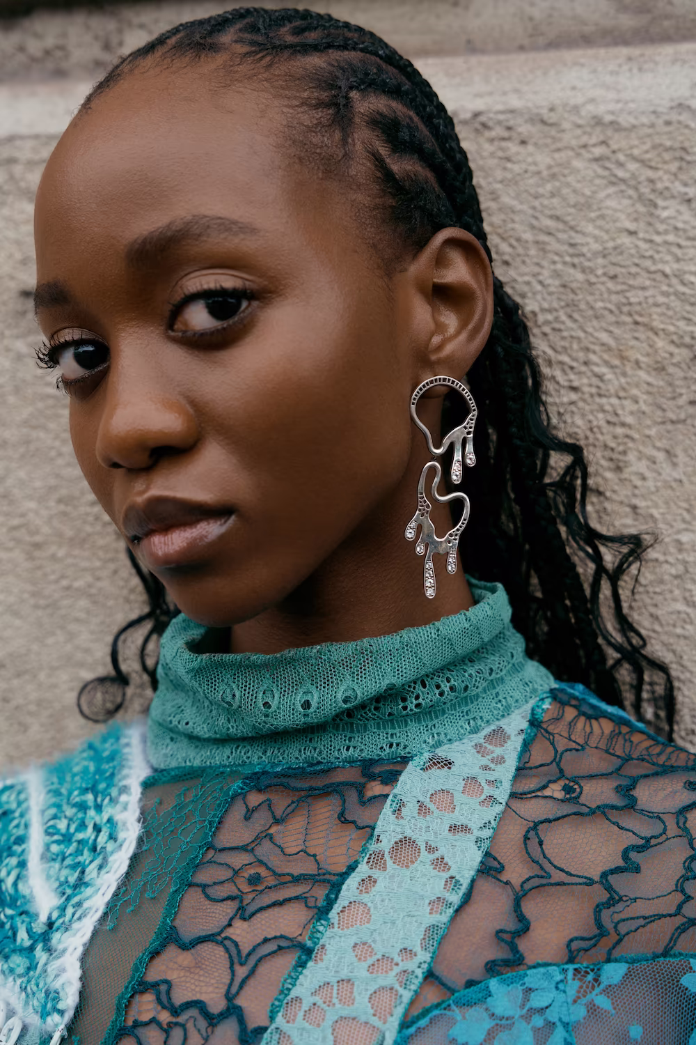 Beauty close-up of a model in a turquoise lace top with an ornate silver earring — fashion editorial portrait