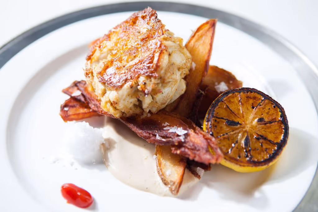 A plate of food with a lemon wedge and a piece of meat.