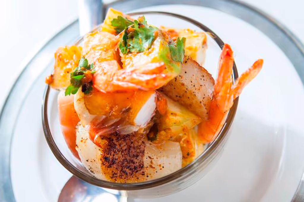 A bowl of shrimp and vegetables with a spoon in it.