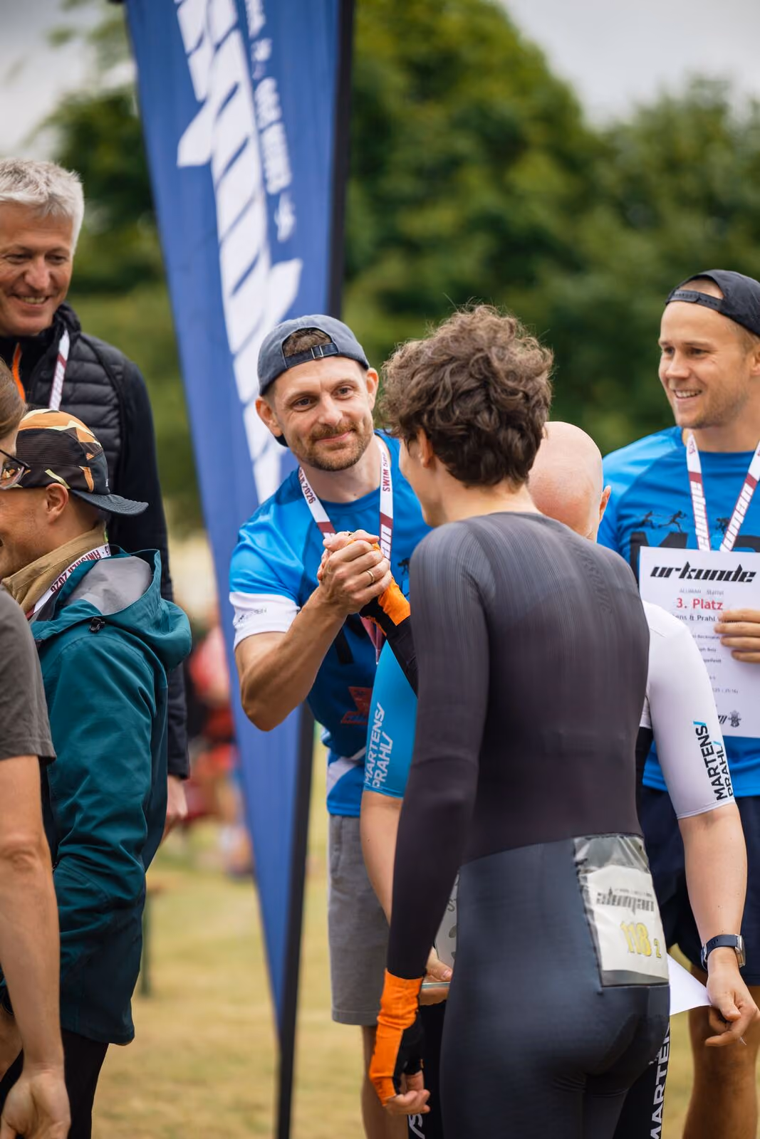 Männer bei Sportveranstaltung begrüßen sich mit Händedruck und lächeln.