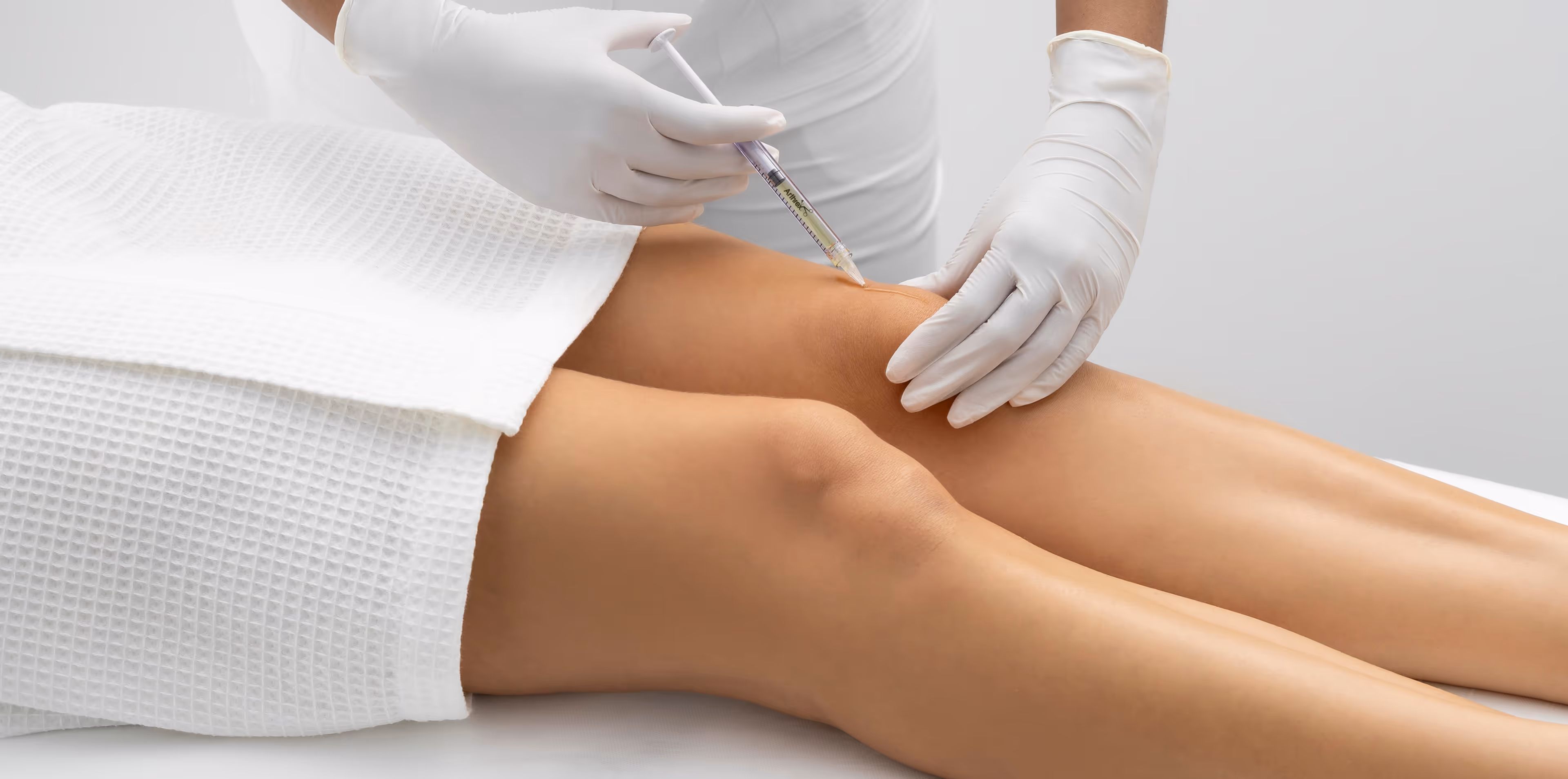 Medical professional injecting a syringe into a patient’s knee for scar treatment with PRP while wearing white gloves.