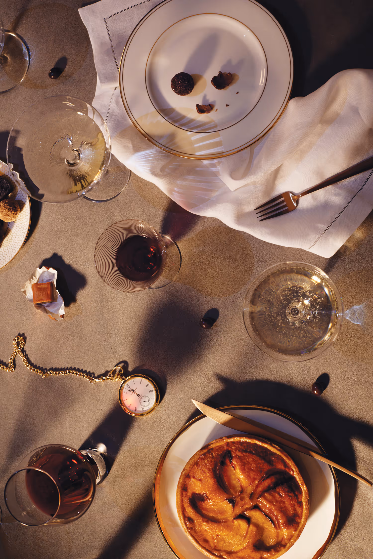 Overhead view of an elegant table setting for The St. Regis Midnight Supper, with desserts, cocktails and a vintage pocket watch.