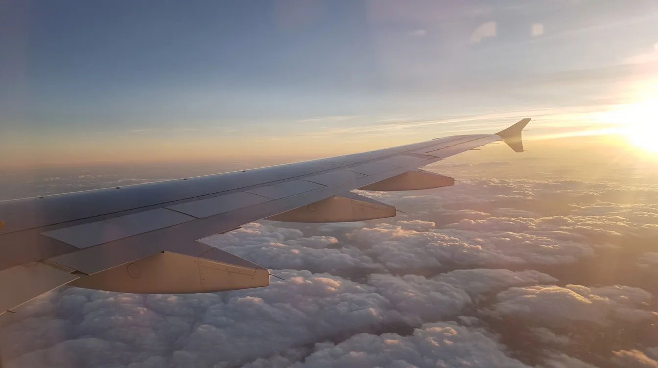 The image depicts the wing of a commercial aircraft soaring above a blanket of fluffy clouds during a vibrant sunrise, symbolizing the potential for the airline industry, including Jet Airways, to restart commercial flights and expand its fleet on both domestic and international routes. The scene captures the essence of civil aviation and the promise of new beginnings in the skies.