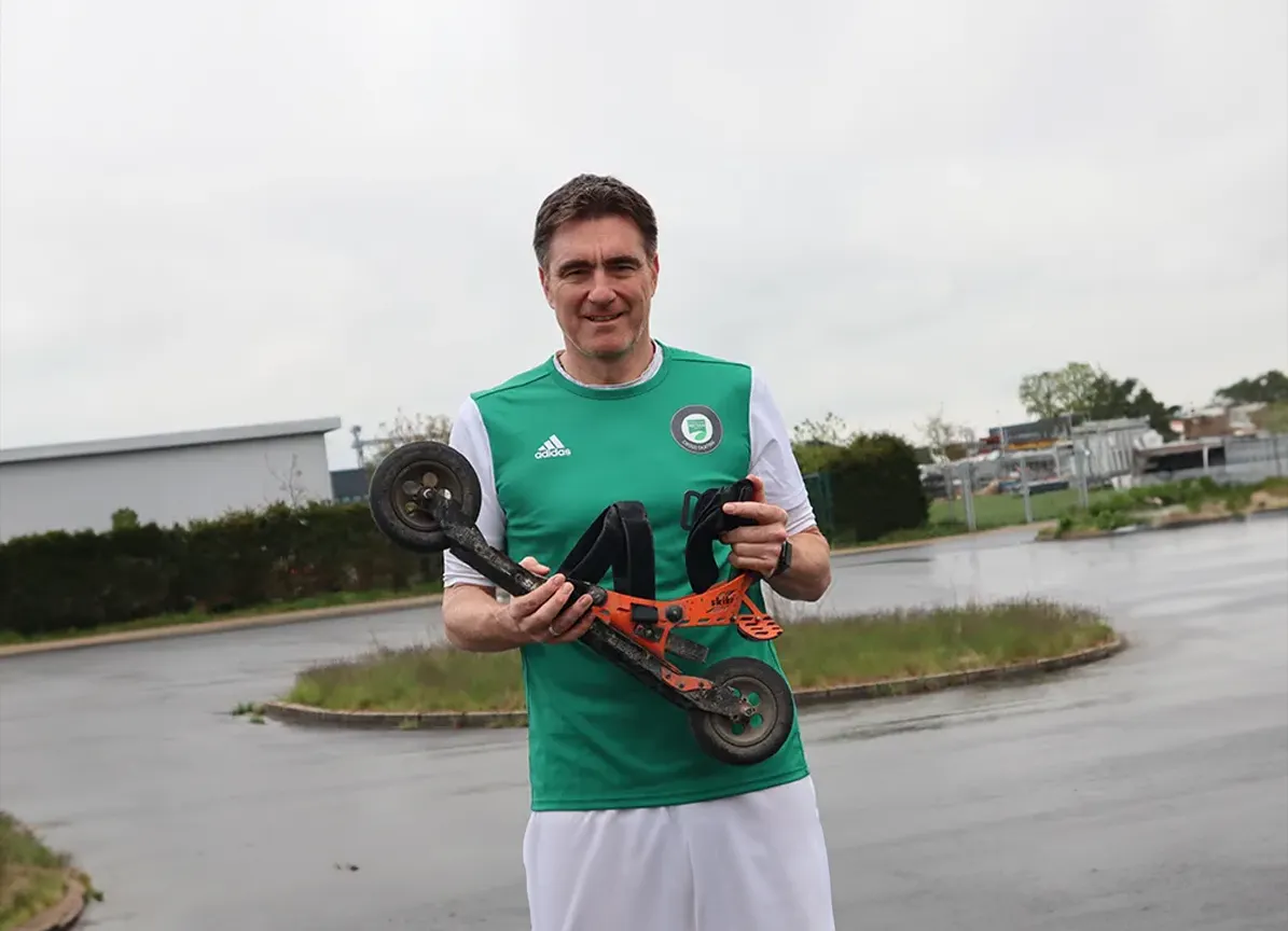 Sportler hält Trainingsgerät im Außenbereich.