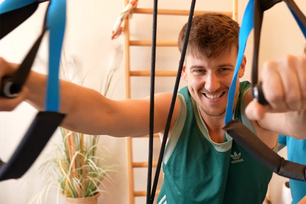 Mann trainiert mit Seilzügen im Fitnessbereich.