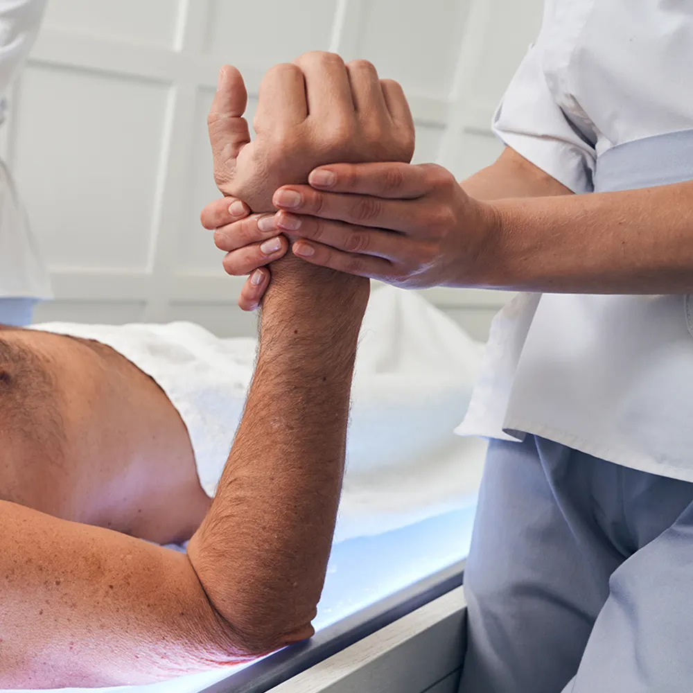 Therapeut massiert den Unterarm einer Person.