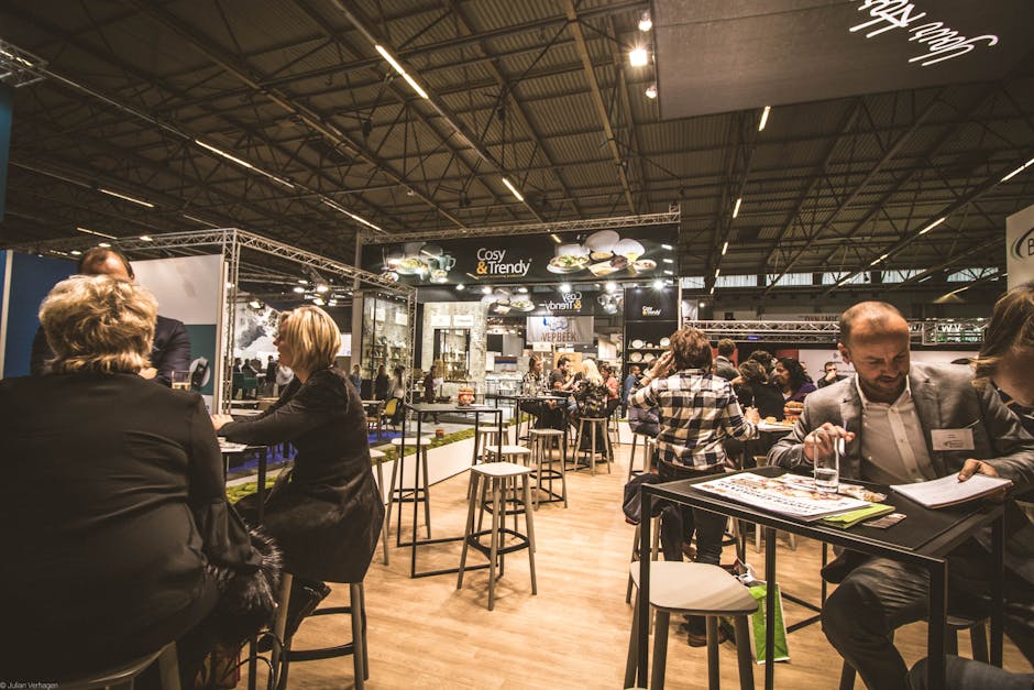 A bustling indoor business expo with professionals networking and engaging at various booths.. Photo by Julian V on Pexels