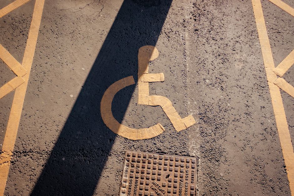 Close-up of a yellow wheelchair symbol painted on asphalt, highlighting accessibility.. Photo by Jakub Pabis on Pexels