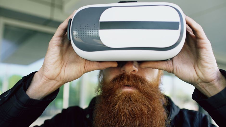 A bearded man using VR headset outdoors, immersing in a virtual experience.. Photo by Vitaly Gariev on Pexels