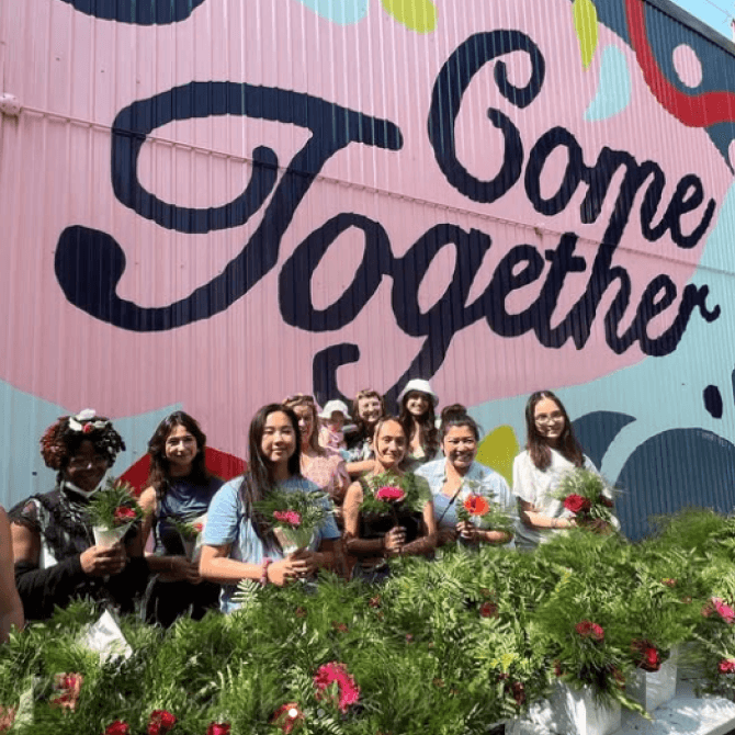 Group of volunteers in front of a mural and garden.