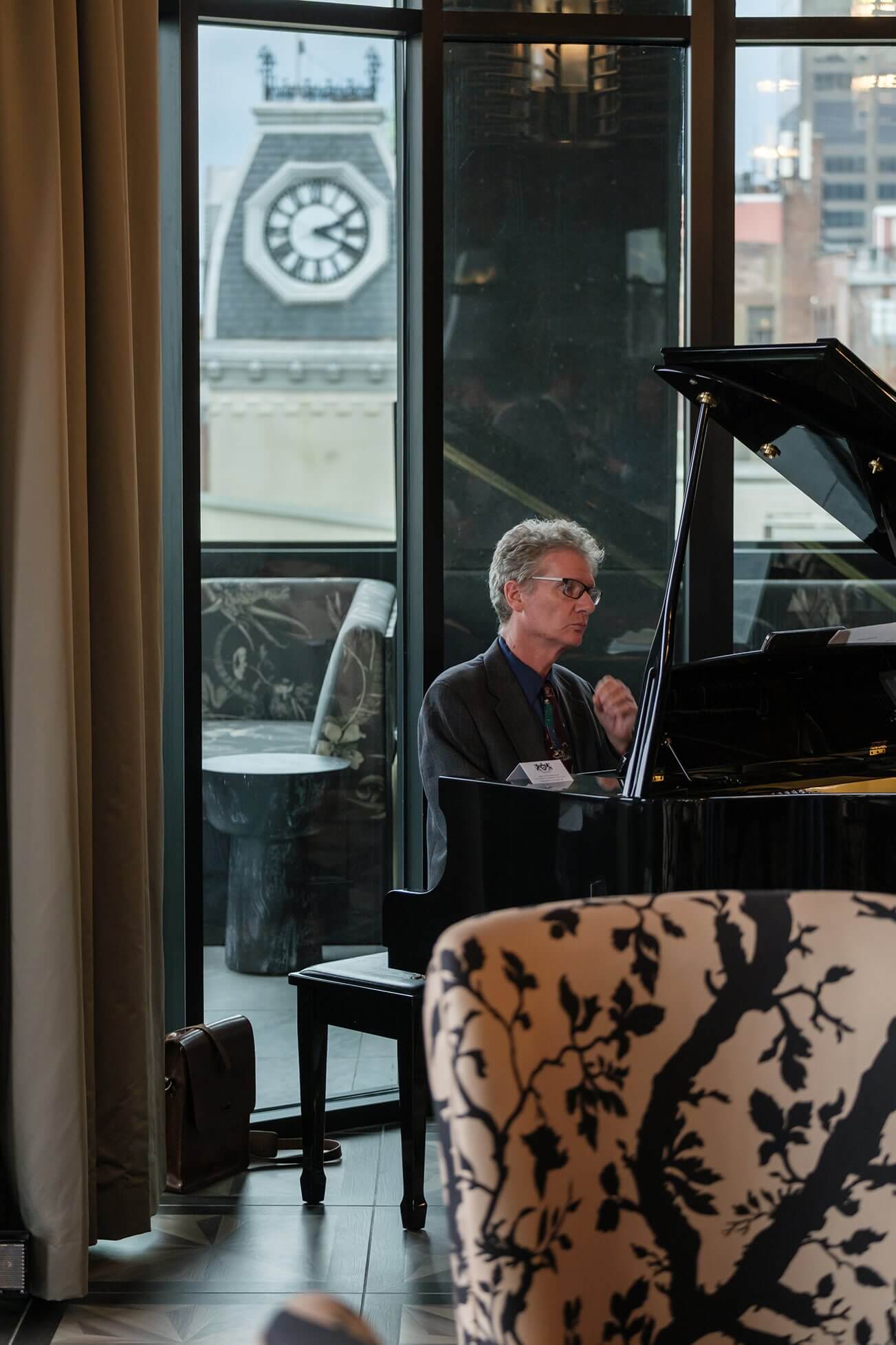 A man sitting at a piano in front of a window.