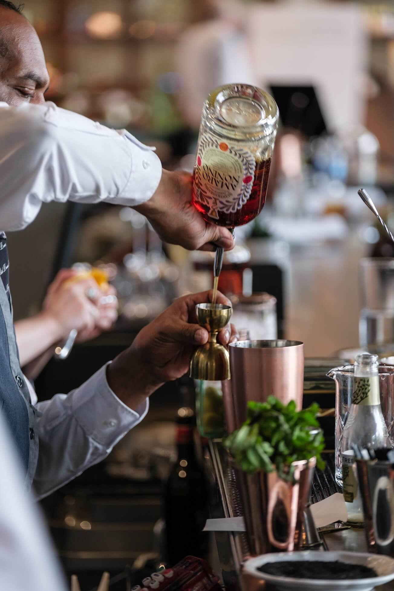 A bartender pouring a drink into a glass.