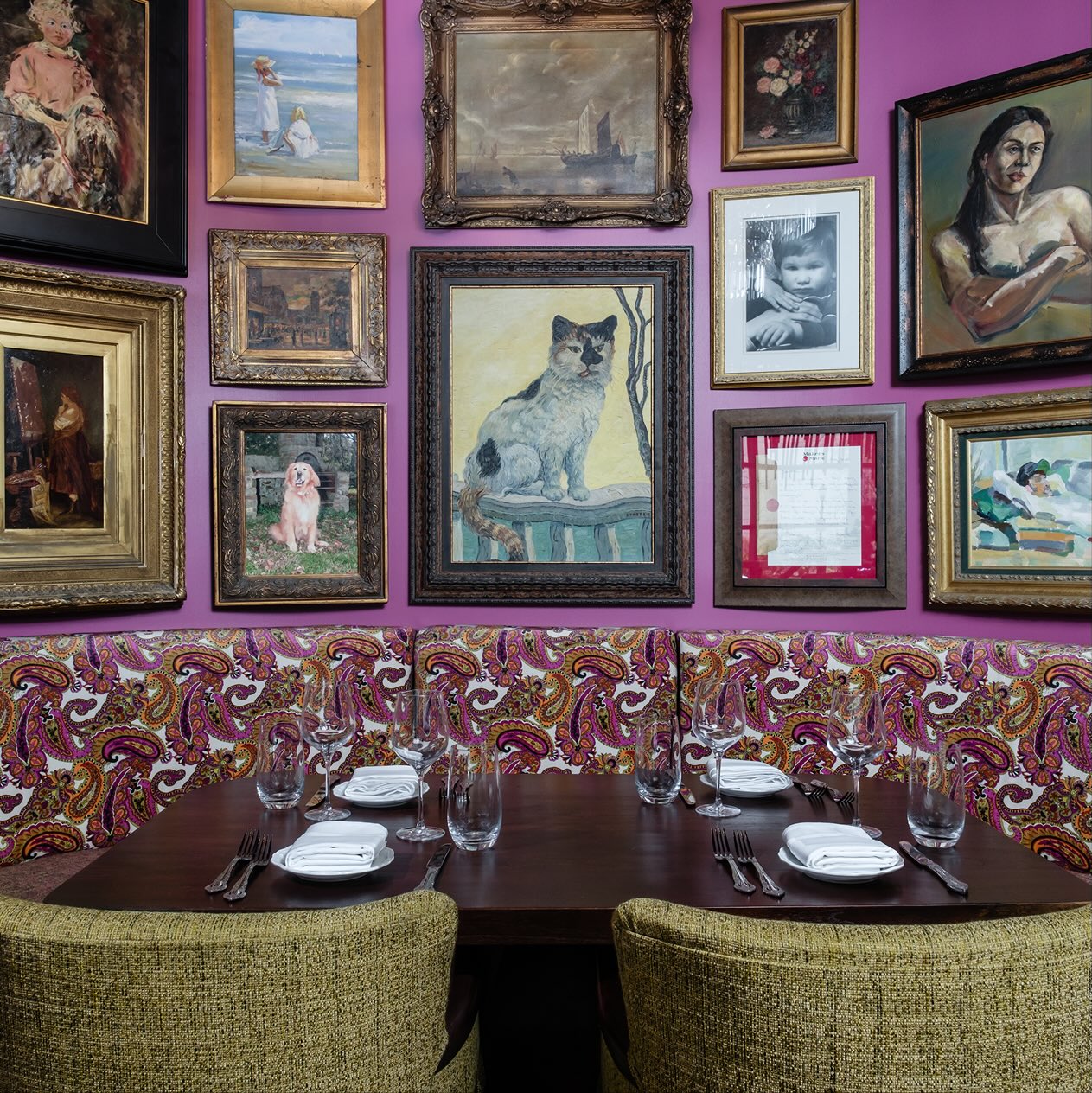 A dining room with purple walls and paintings on the wall.