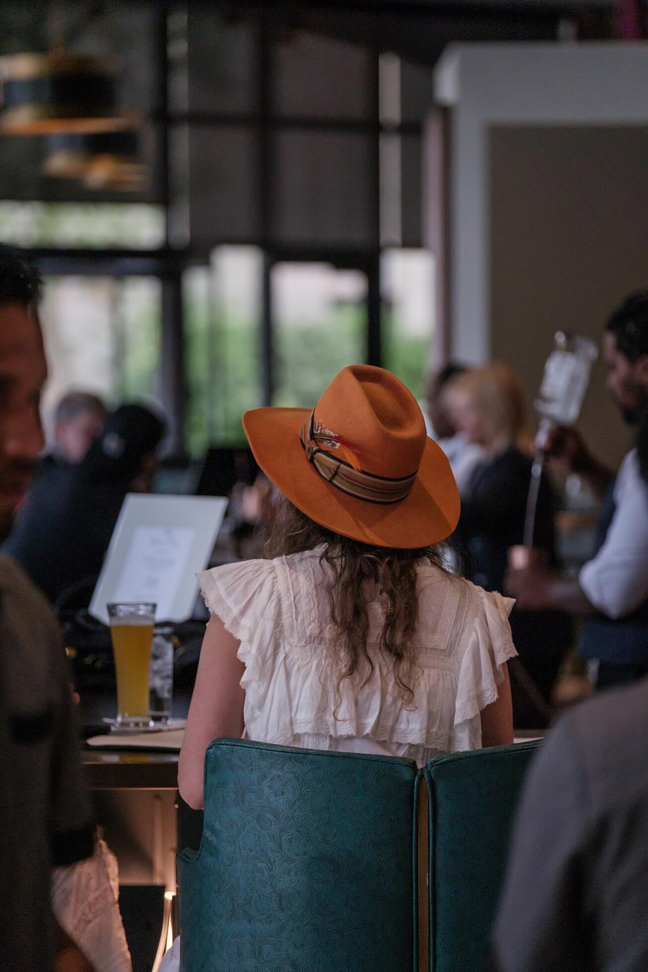 A woman sitting at a table with a hat on her head.