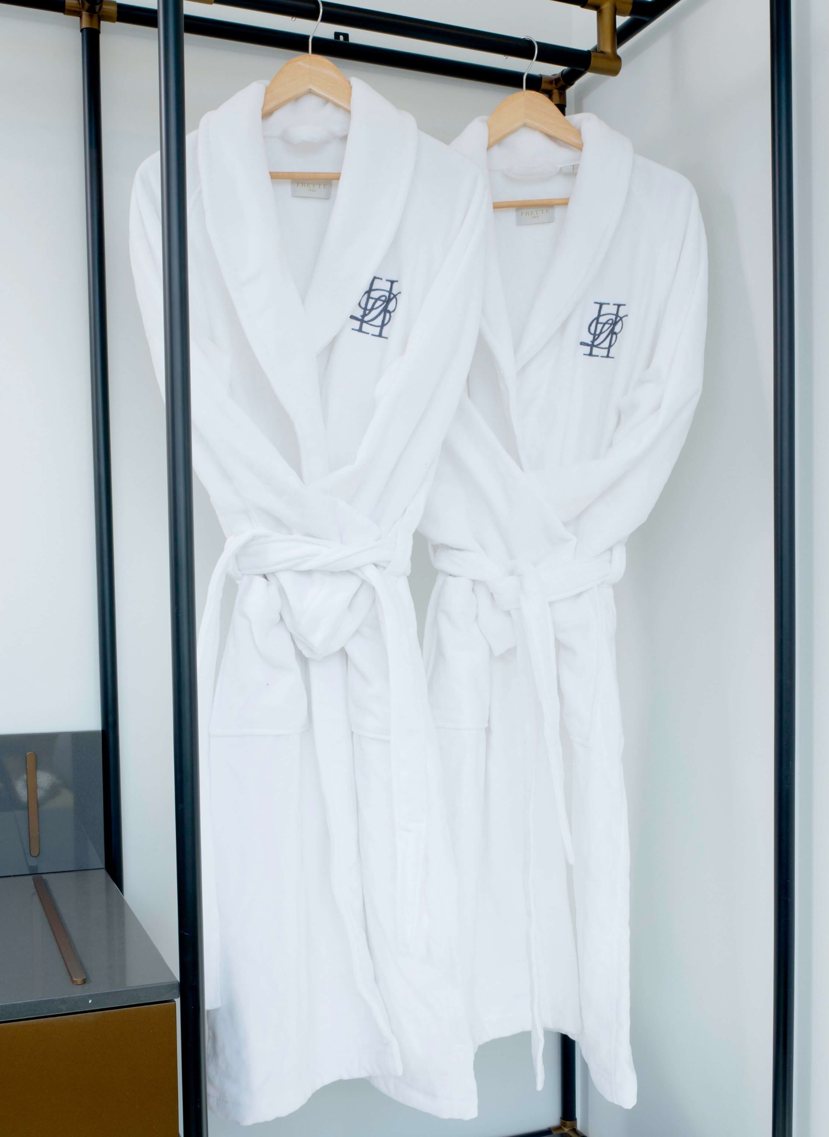 A couple of white robes hanging on a rack.