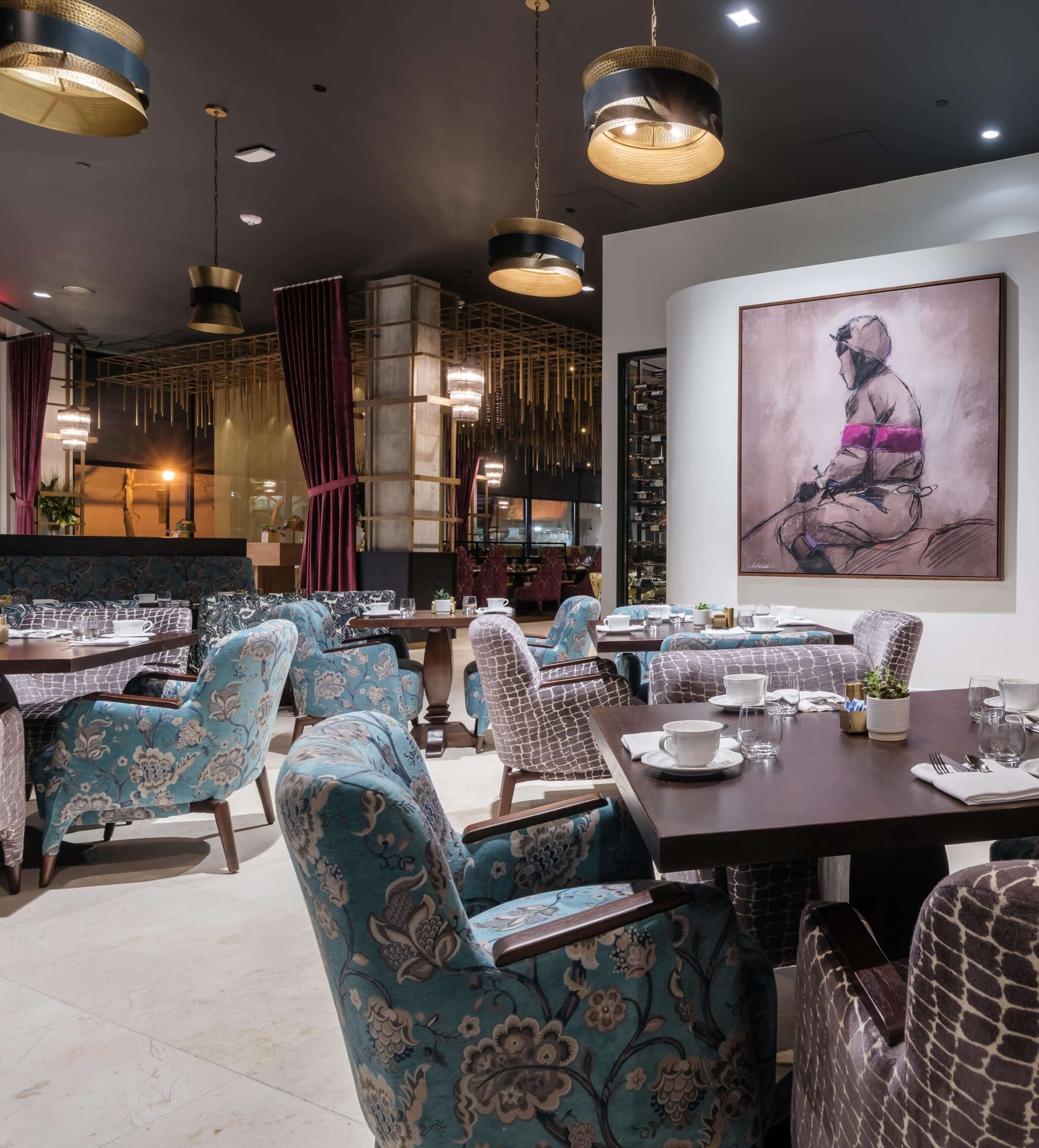 A dining room with blue chairs and a painting on the wall.