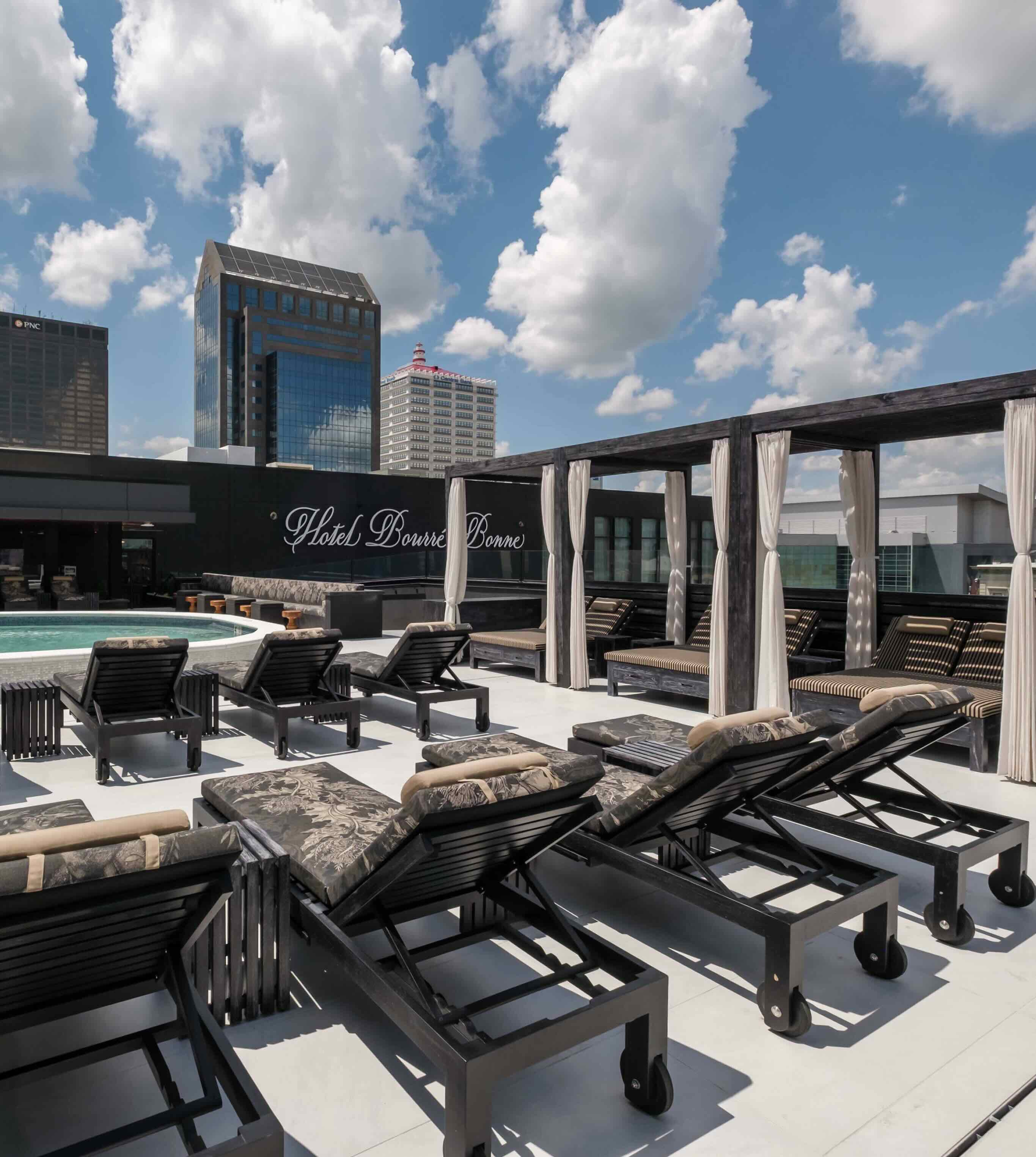 A rooftop with lounge chairs and a swimming pool.