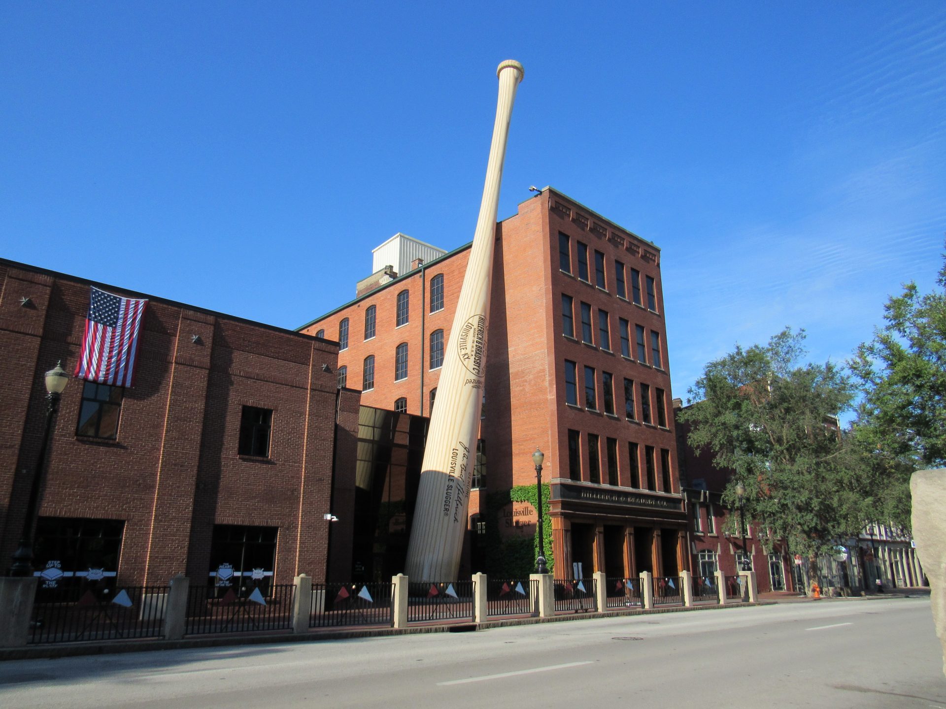 A tall building with a giant baseball bat sticking out of it's side.