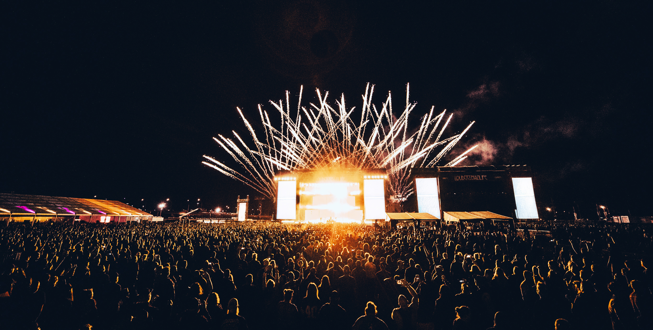 A large crowd of people watching a fireworks show.