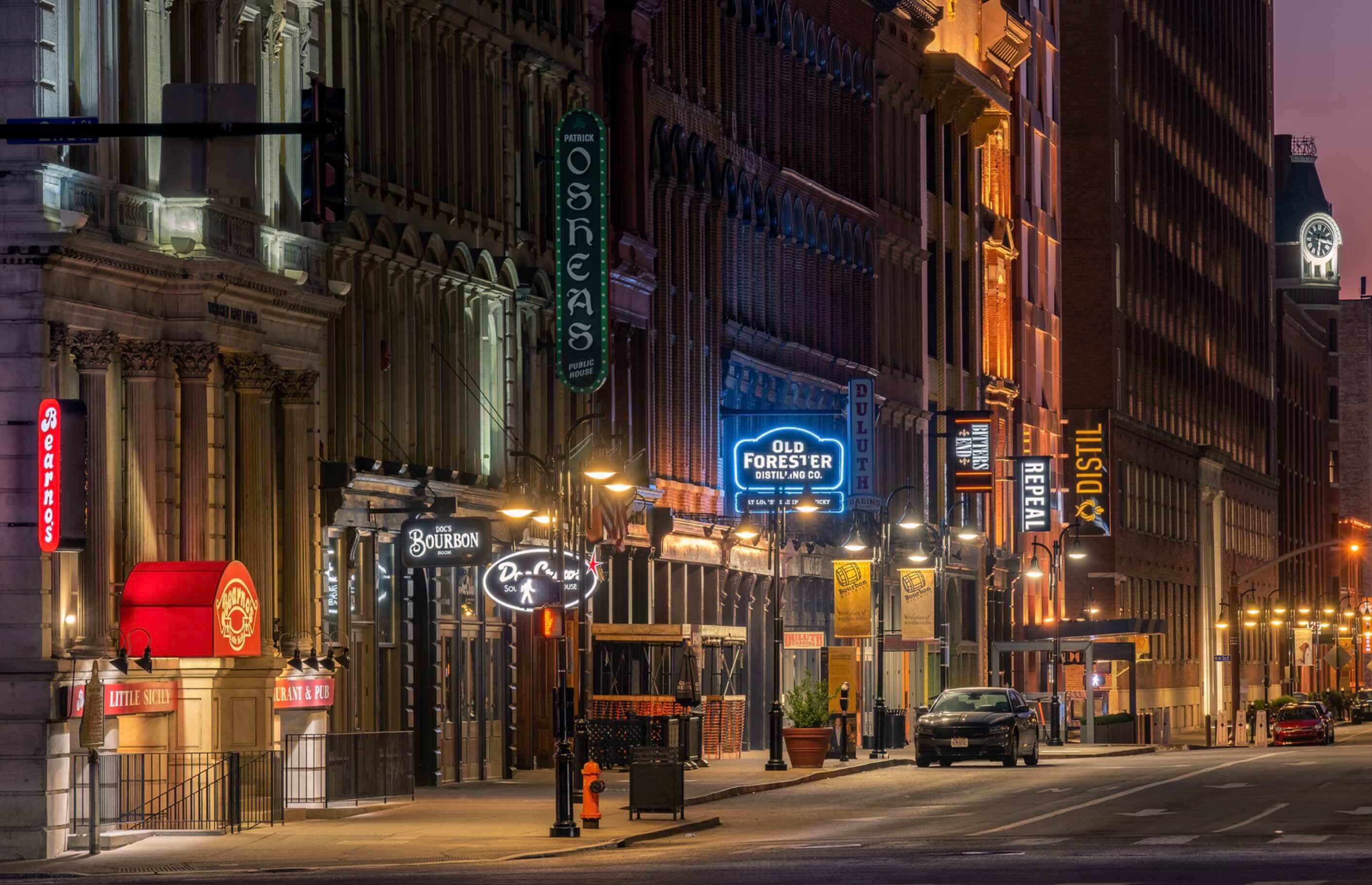 A city street at night with tall buildings.