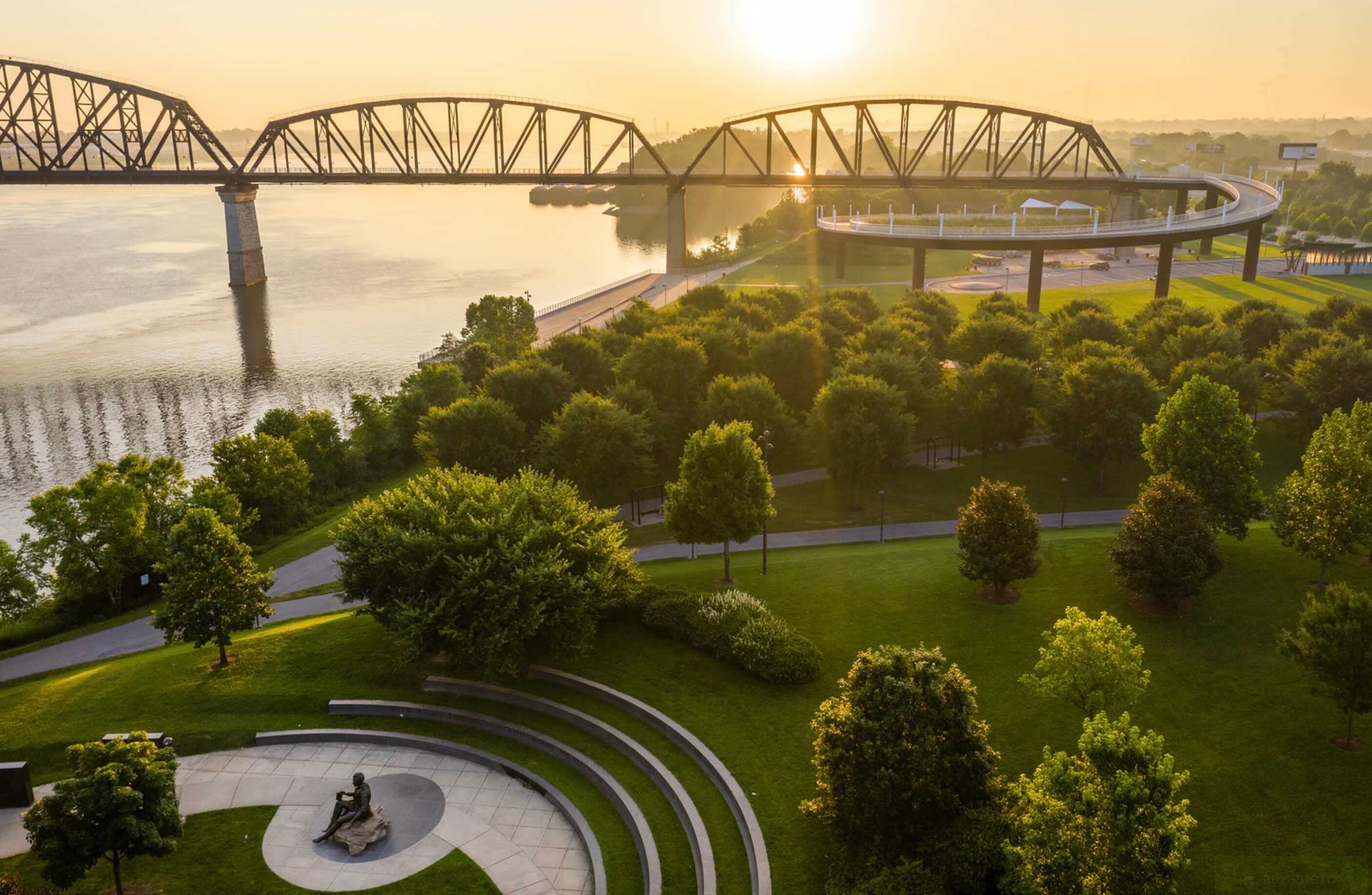 An aerial view of a park with a bridge in the background.
