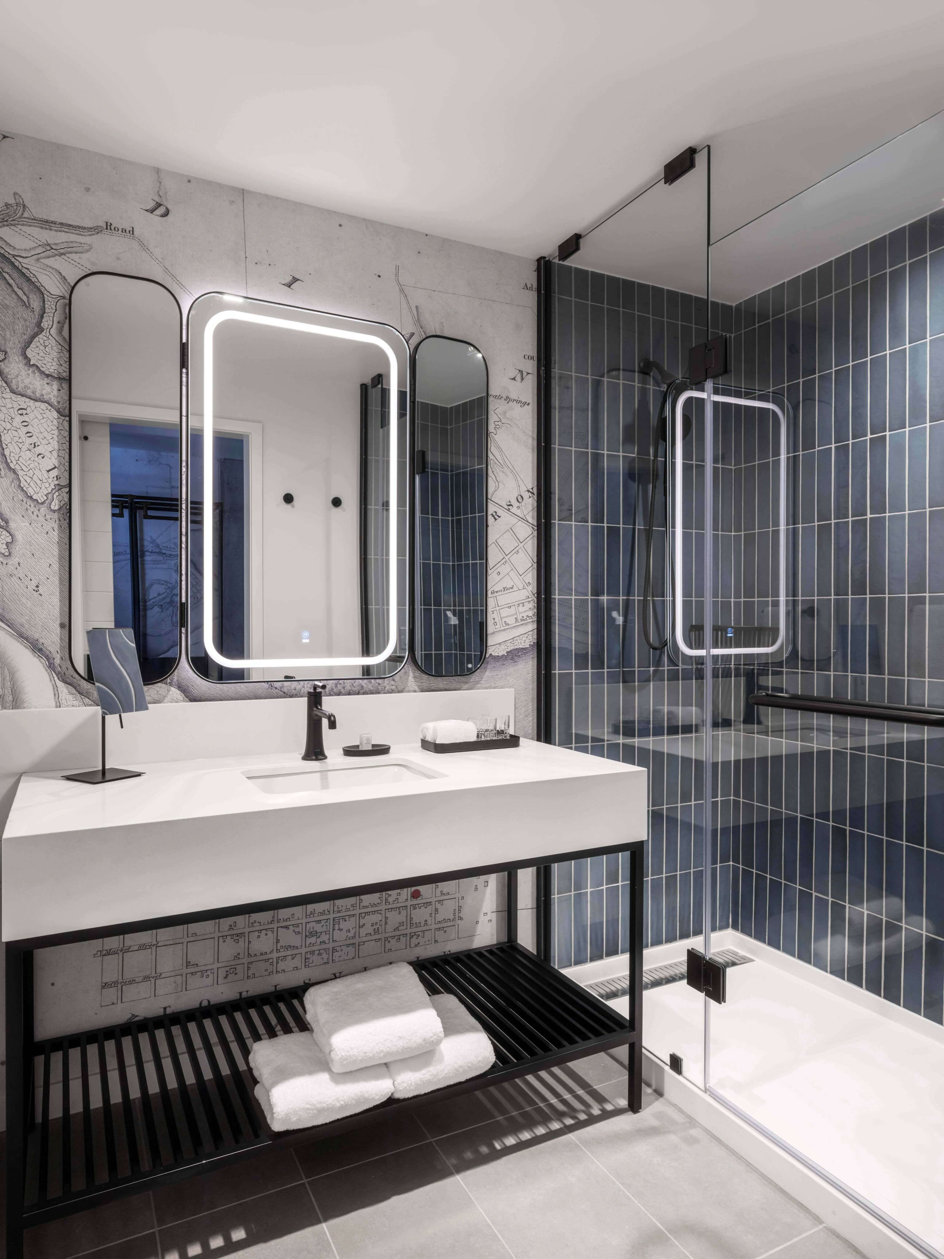A bathroom with a sink, mirror and shower stall.