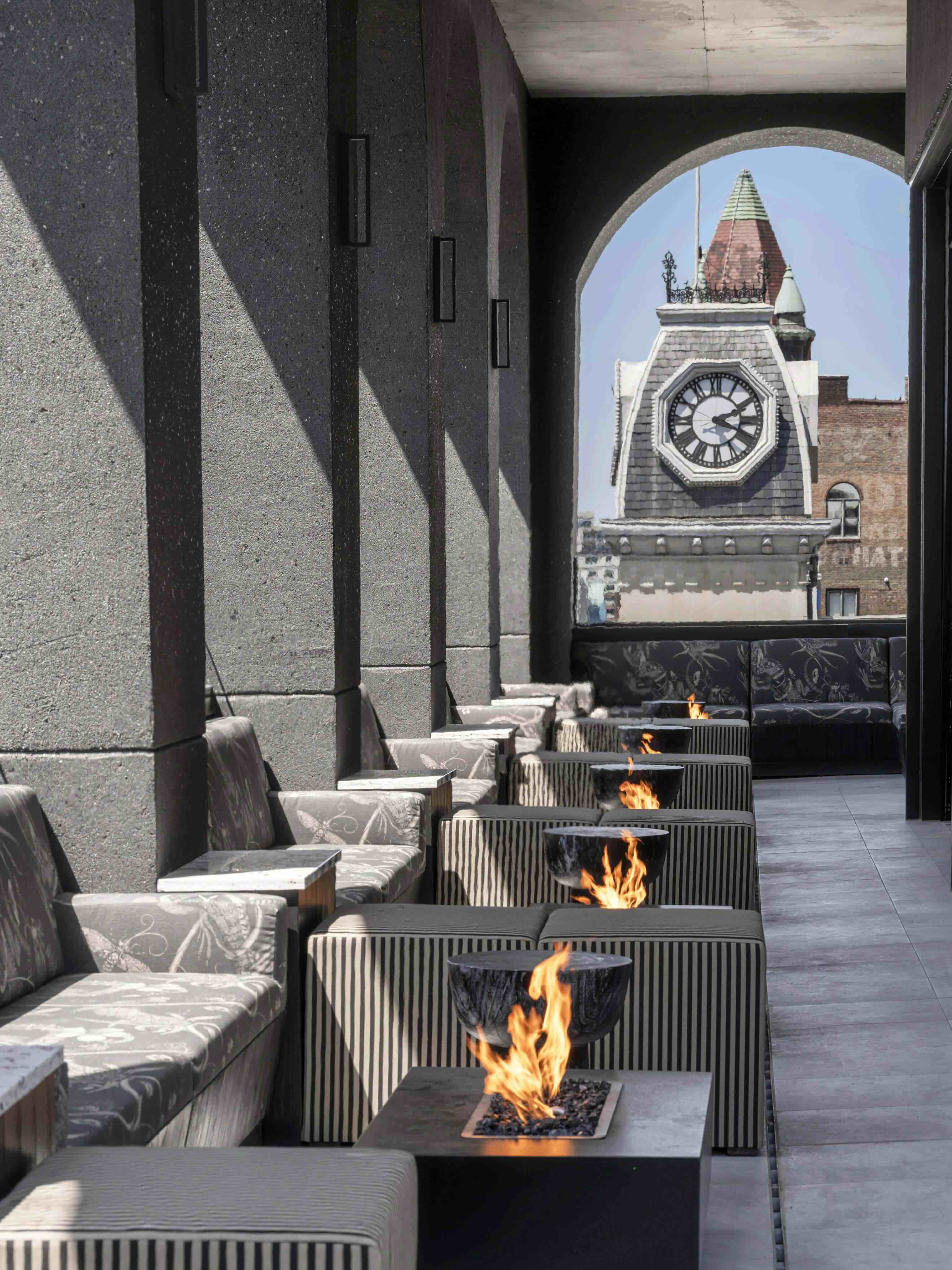 A clock tower in the distance with a fire pit in the foreground.
