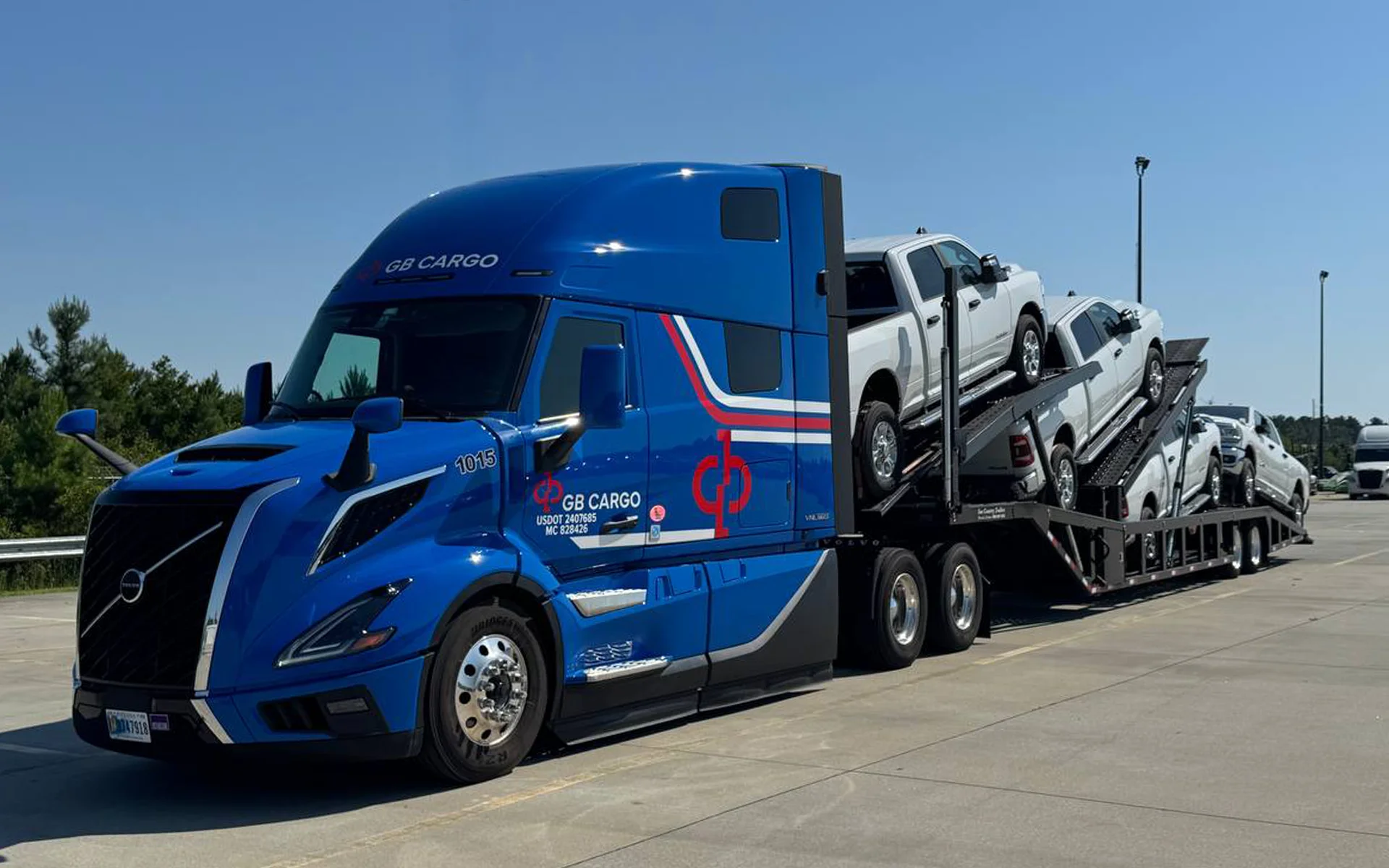 A GB Cargo's car hauling truck loaded with cars parked in a parking lot.