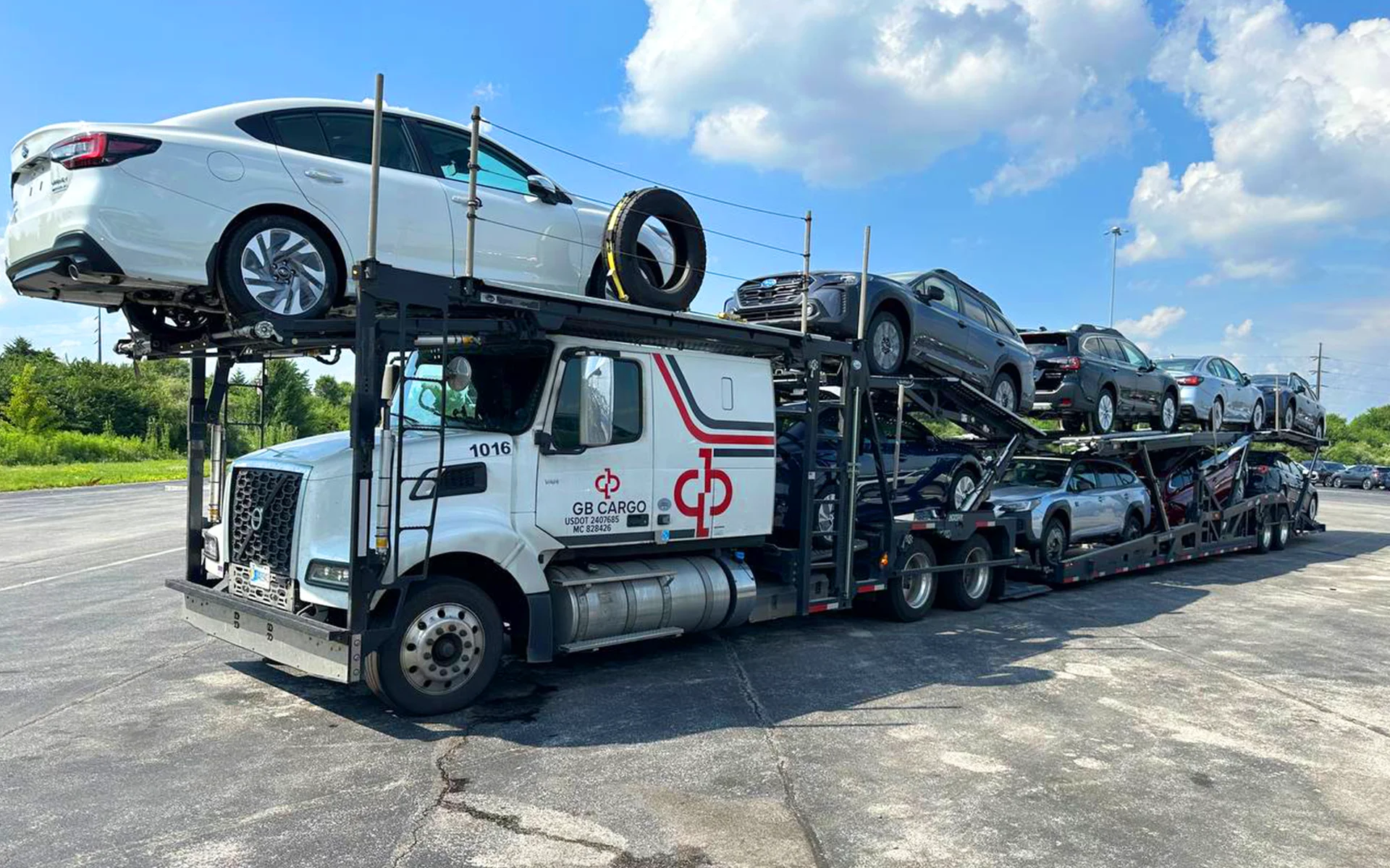 A loaded GB Cargo car hauling truck in the parking lot of a OEM.