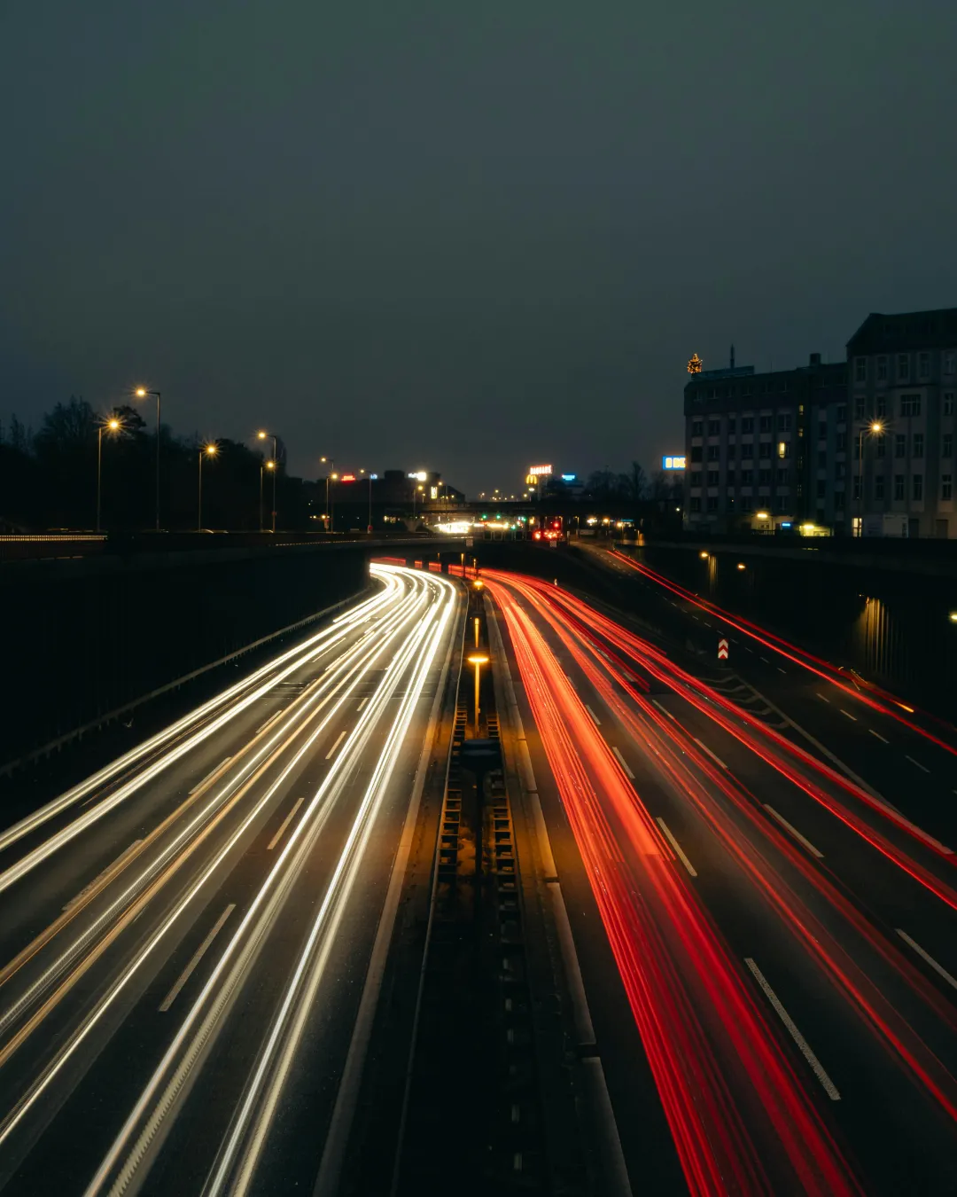 Long-exposure photo of a multi-lane motorway at night, with white and red light trails from passing cars.