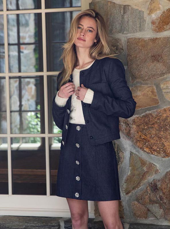 A woman standing in a room wearing a skirt and boots.